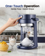 Hand pressing the top button as the machine shaves ice into a bowl on a kitchen counter
